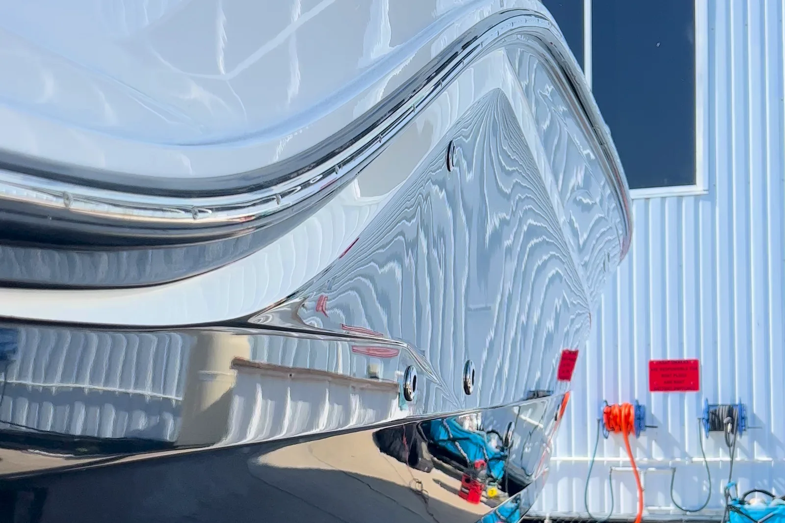 A white hull on its lift, the building behind it reflected in the gloss.